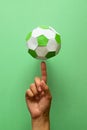 Hand spinning paper soccer ball on green background. Origami. Paper craft. Soccer game concept Royalty Free Stock Photo