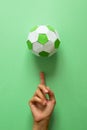 Hand spinning paper soccer ball on green background. Origami. Paper craft. Soccer game concept Royalty Free Stock Photo