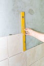 Hand with spirit level against gray wall with tiles Royalty Free Stock Photo