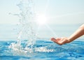 Hand splashing clean water in sun rays