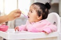 Hand, spoon and child food in chair for baby development, nutrition meal or dinner snack. Kid, feed and eating breakfast