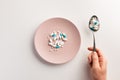 Hand with spoon of pills and plate with pills Royalty Free Stock Photo