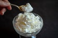 hand with spoon taking a dollop of whipped cream