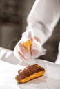 Hand spraying decoration over chocolate covered eclair