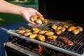 hand spreading butter over smoking clams on a grill