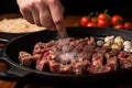 hand sprinkling garlic over sizzling steak tips
