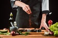 Hand sprinkling paprika onto salmon fillets. Cooking fish steak Royalty Free Stock Photo