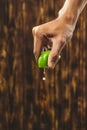 Hand squeeze lime with lime drop on wooden background Royalty Free Stock Photo