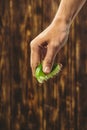 Hand squeeze lime with lime drop on wooden background Royalty Free Stock Photo