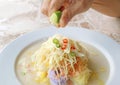 Hand Squeezing Lime Juice into Khanom Chin Sao Nam, a Tasty Thai Rice Vermicelli Salad Soup