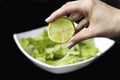 Hand squeezing half of a fresh lime on a black background Royalty Free Stock Photo