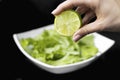 Hand squeezing half of a fresh lime on a black background Royalty Free Stock Photo