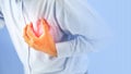Hand squeezing the left chest pain with red light on blue background concept of heart attack Royalty Free Stock Photo