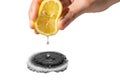 Hand squeezing lemon half over a black object with a bubbling reaction Royalty Free Stock Photo