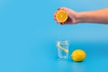 hand squeezing lemon juice in glass beaker with a slice of lemon and a lemon cut in half near it Royalty Free Stock Photo