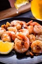 A hand squeezing lemon juice on roasted, grilled shrimp