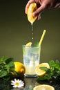 Hand squeezing lemon in lemonade, on dark background Royalty Free Stock Photo