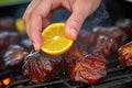 hand squeezing lemon onto burnt ends on the bbq