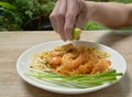 Hand squeezing lemon to Pad Thai stir fried rice noodles with shrimp and egg on plate Royalty Free Stock Photo