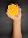 Hand squeezing orange in detail with black background, orange concept Royalty Free Stock Photo