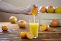 Hand squeezing orange juice into a glass on a wooden table Royalty Free Stock Photo