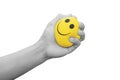 Hand squeezing smiling face yellow stress ball, isolated on white background Royalty Free Stock Photo