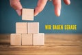 Hand is stacking blank cubes and the message `under construction ` in German