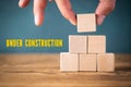 Hand is stacking blank cubes and the message `under construction `