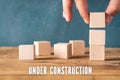 Hand is stacking blank cubes and the message `under construction `
