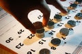 A Hand Stacking Coins/Money on A Calendar