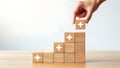 Hand stacking wooden blocks with white plus signs in ascending order growth success Royalty Free Stock Photo