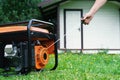 Hand starts a portable electric generator in front of a summer house in summer Royalty Free Stock Photo