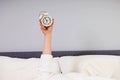 Hand stick out under the blanket showing alarm clock. Royalty Free Stock Photo