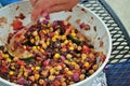 Hand stirring fresh black bean and corn salad in a large serving bowl Royalty Free Stock Photo