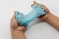 Hand strecthing transparent blue glitter slime on white