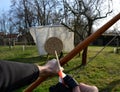 Hand stretches bowstring in archery gloves near wooden tissue bow arrow with feather wings wood target straw target aim shoot Royalty Free Stock Photo