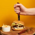 Hand stubbing burger with knife