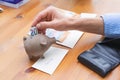 Hand stuffing a bill into a piggy bank for savings. Copy space Royalty Free Stock Photo