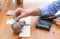 Hand stuffing a bill into a piggy bank for savings. Copy space Royalty Free Stock Photo