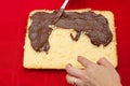 Hand stuffing homemade cake with chocolate ganache. Isolated on red background. Top view. Close-up