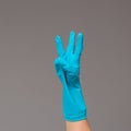 Hand in surgical glove shows three fingers on neutral background. Copy space. Royalty Free Stock Photo