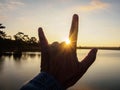 Hand symbol against sunlight at sunrise