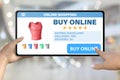 Hand with tablet computer tapping the button buy online on bokeh business background - online shopping technology concept