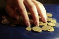 The hand takes the coins. Close your savings with your hand. Coins on a blue background Royalty Free Stock Photo