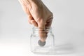 The hand takes the last coin from the piggy bank, close-up. Quarter dollar coin in a glass bottle, isolate on a white background. Royalty Free Stock Photo