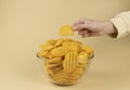 The hand takes potato chips from the glass bowl. The hand with the chips. Royalty Free Stock Photo