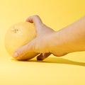 Hand takes or puts on the table yellow grapefruit. Setting on a pastel background