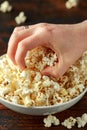 Hand takes salty popcorn from the bowl