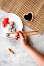 Hand takes sushi roll with salmon and avocado with chopstick. Grey stone and mat background top view copyspace Royalty Free Stock Photo