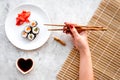 Hand takes sushi roll with salmon and avocado with chopstick. Grey stone and mat background top view Royalty Free Stock Photo